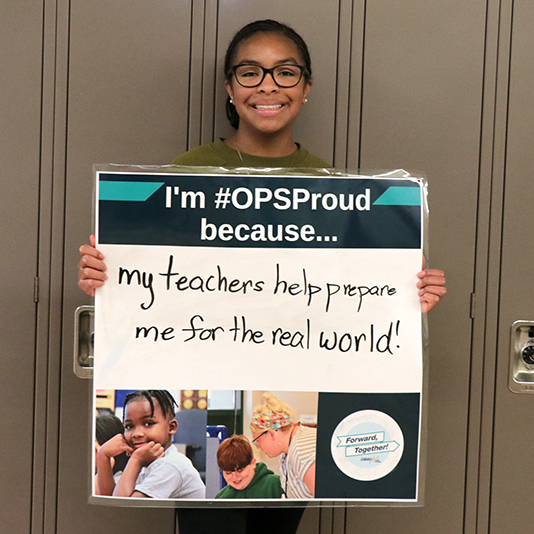 Student holding sign saying I'm OPS Proud because my teachers help prepare me for the real world